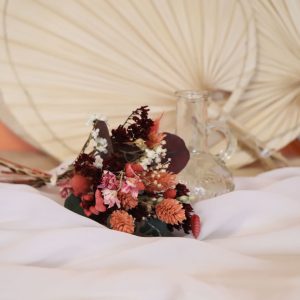 zoom sur le bouquet rose avec des fleurs rouges et roses et la fiole transparente à côté